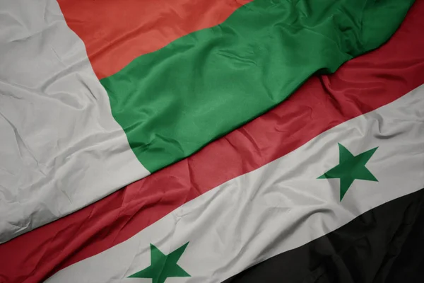 Ondeando colorida bandera de Siria y bandera nacional de madagascar . —  Fotos de Stock
