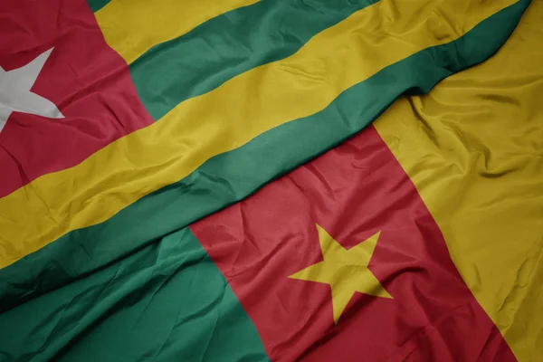 Machanie barwną flagą Kamerunu i flagą narodową togo. — Zdjęcie stockowe