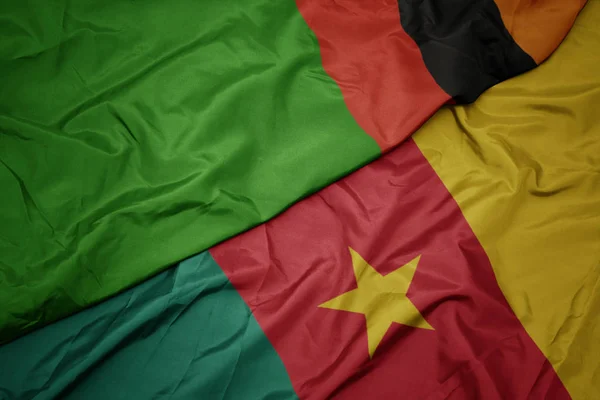 Ondeando colorida bandera de camerún y bandera nacional de zambia . — Foto de Stock