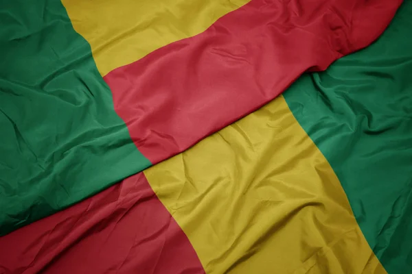 Waving colorful flag of guinea and national flag of benin. — Stock Photo, Image