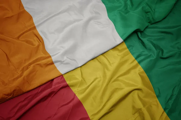Sventolando bandiera colorata di ghinea e bandiera nazionale di cote divoire . — Foto Stock
