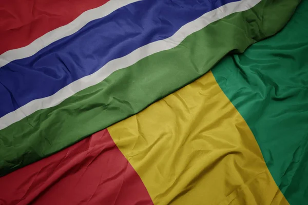 Acenando bandeira colorida da Guiné e bandeira nacional da Gâmbia . — Fotografia de Stock