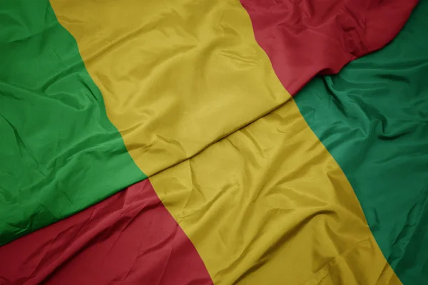 Ondeando colorida bandera de Guinea y bandera nacional de Malí . — Foto de Stock