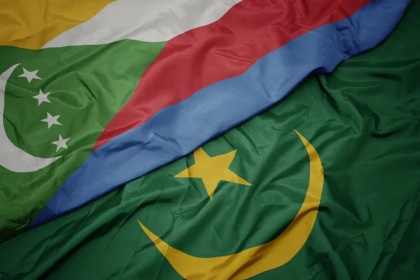 Waving colorful flag of mauritania and national flag of comoros. — Stock Photo, Image