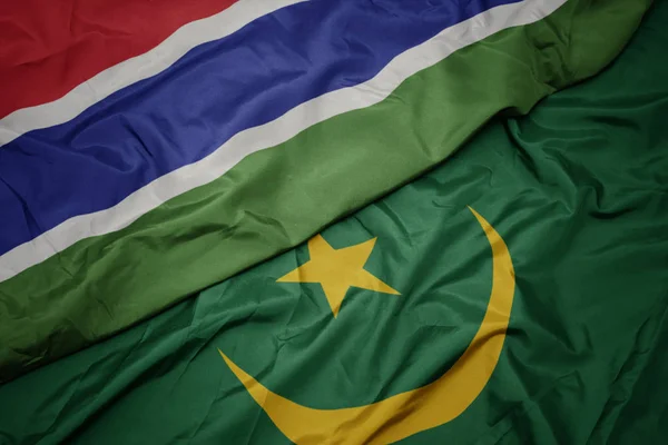 Mávání barevnou vlajkou mauritánie a národní vlajky gamia. — Stock fotografie