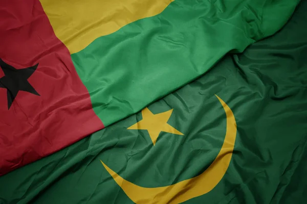 Waving colorful flag of mauritania and national flag of guinea bissau. — Stock Photo, Image