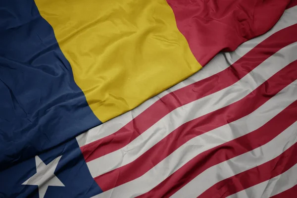 Zwaaiende kleurrijke vlag van liberia en nationale vlag van chad. — Stockfoto