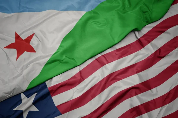 Ondeando colorida bandera de liberia y bandera nacional de djibouti . — Foto de Stock