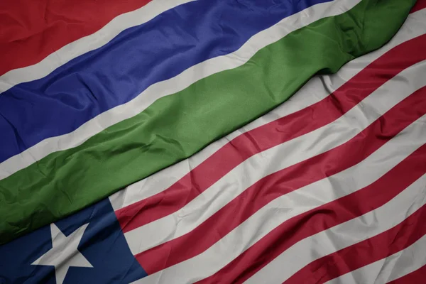 Acenando bandeira colorida da Libéria e bandeira nacional da Gâmbia . — Fotografia de Stock