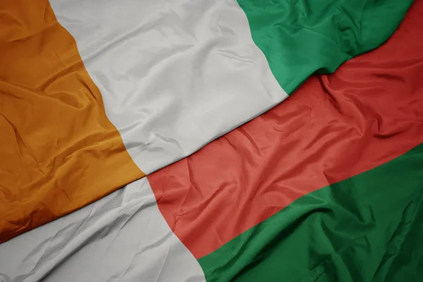 Schwenken bunte Fahne von Madagaskar und Nationalflagge von Cote divoire. — Stockfoto