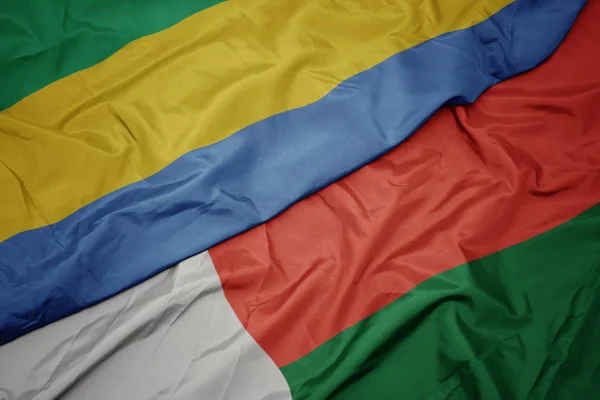 Machanie barwną flagą Madagaskaru i flagą narodową Gabonu. — Zdjęcie stockowe