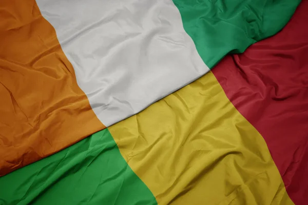 Ondeando colorida bandera de mali y bandera nacional de cote divoire . — Foto de Stock