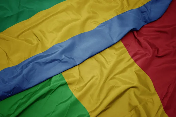 Ondeando colorida bandera de mali y bandera nacional de gabón . — Foto de Stock