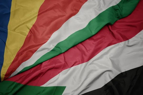 Sventolando bandiera colorata di bandiera sudana e nazionale di seychelles . — Foto Stock