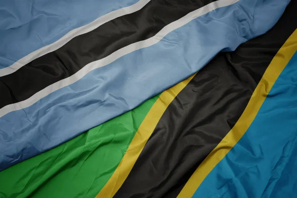 Ondeando colorida bandera de tanzania y bandera nacional de botswana . —  Fotos de Stock