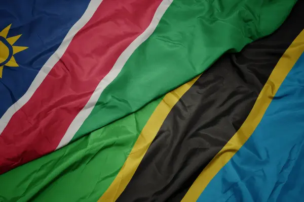 Ondeando colorida bandera de tanzania y bandera nacional de namibia . —  Fotos de Stock