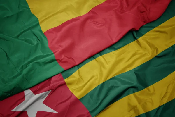 Ondeando colorida bandera de togo y bandera nacional de benin . — Foto de Stock