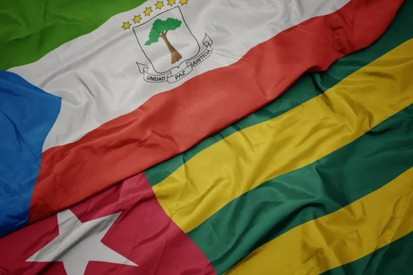 Sventolando bandiera colorata del togo e bandiera nazionale della Guinea equatoriale . — Foto Stock