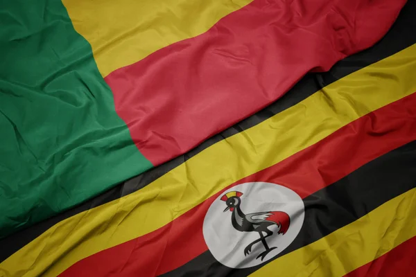 Размахивая красочным флагом Уганды и национальным флагом Бенина . — стоковое фото