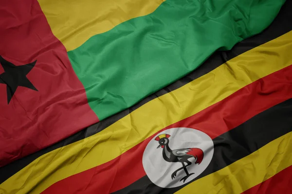 Размахивая красочным флагом Уганды и национальным флагом Гвинеи Бисау . — стоковое фото