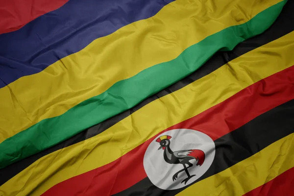 Sventolando bandiera colorata di uganda e bandiera nazionale di mauritius . — Foto Stock