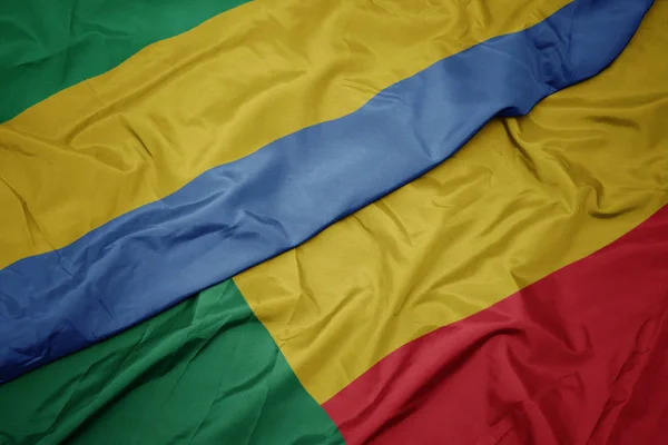 Ondeando colorida bandera de benin y bandera nacional de gabón . — Foto de Stock