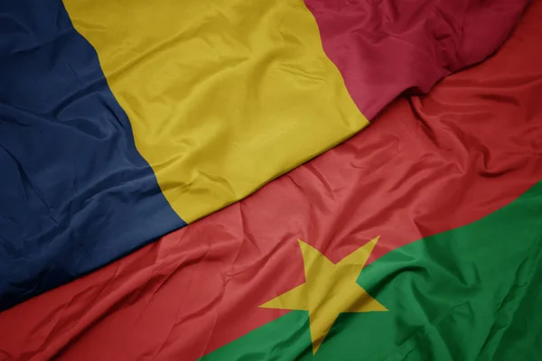 Ondeando colorida bandera de Burkina faso y bandera nacional de Chad . — Foto de Stock