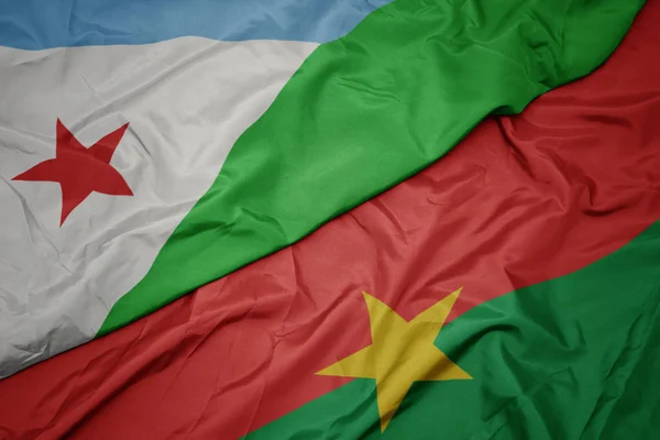 Ondeando colorida bandera de burkina faso y bandera nacional de djibouti . — Foto de Stock