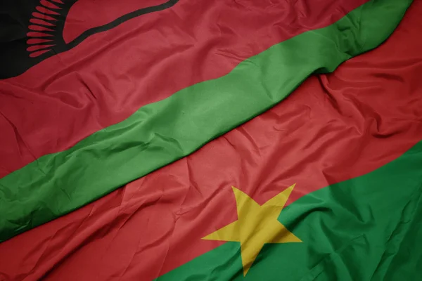 Ondeando colorida bandera de Burkina faso y bandera nacional de Malawi . — Foto de Stock