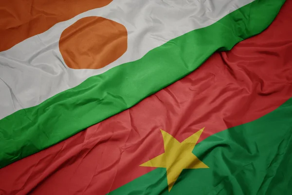 Ondeando colorida bandera de Burkina faso y bandera nacional de Níger . — Foto de Stock