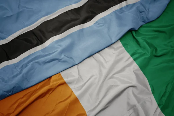Agitant drapeau coloré de cote divoire et drapeau national du Botswana . — Photo