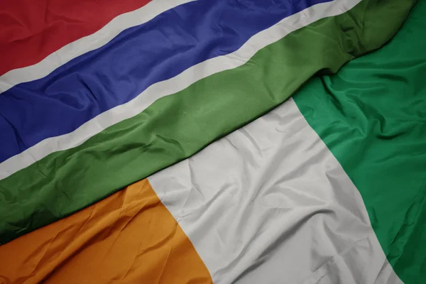 Schwenken bunte Flagge der Cote divoire und Nationalflagge von Gambia. — Stockfoto