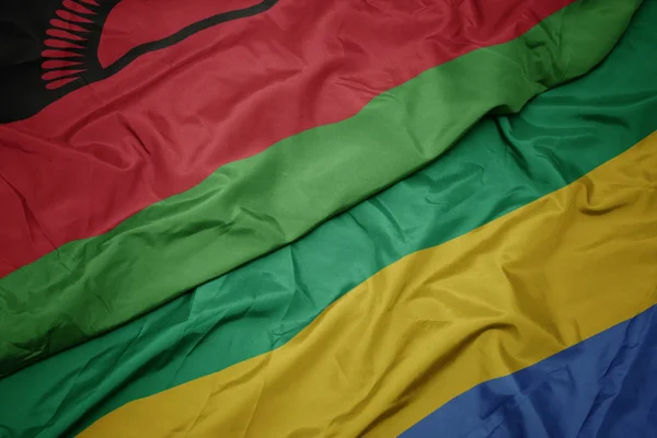 Размахивая красочным флагом Габона и национальным флагом Малави . — стоковое фото