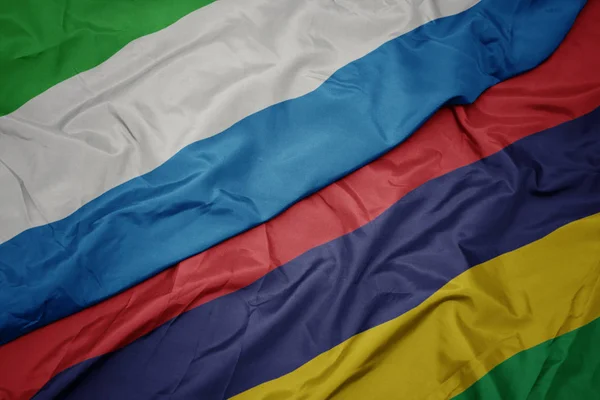 Ondeando colorida bandera de Mauricio y bandera nacional de Sierra Leona . — Foto de Stock