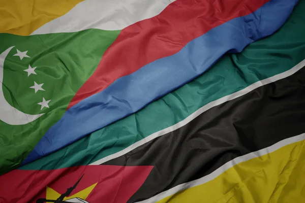 Ondeando colorida bandera de Mozambique y bandera nacional de las comoras . — Foto de Stock
