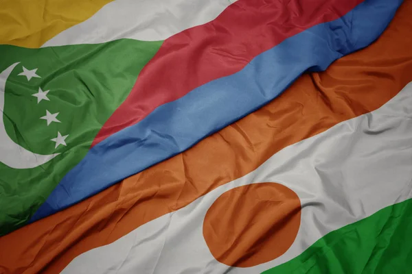 Waving colorful flag of niger and national flag of comoros. — Stock Photo, Image