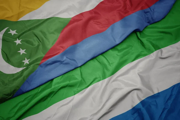 Waving colorful flag of sierra leone and national flag of comoros. — Stock Photo, Image