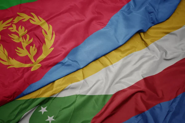 Ondeando colorida bandera de comoras y bandera nacional de eritrea . — Foto de Stock