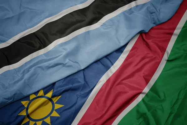 Ondeando colorida bandera de namibia y bandera nacional de botswana . —  Fotos de Stock