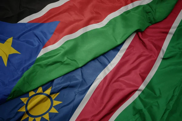 Ondeando colorida bandera de namibia y bandera nacional de sudan del sur . —  Fotos de Stock