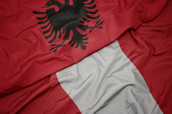 Sventolando bandiera colorata di perù e bandiera nazionale di albania . — Foto Stock