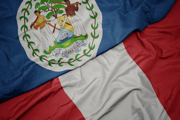 Ondeando colorida bandera de perú y bandera nacional de Belice . — Foto de Stock