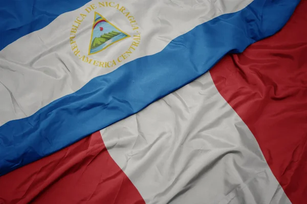 Ondeando colorida bandera de perú y bandera nacional de nicaragua . — Foto de Stock