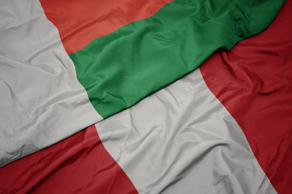 Lobogtató színes zászló a peru és a nemzeti zászló Madagaszkár. — Stock Fotó