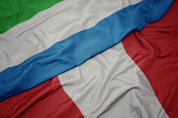 Размахивая красочным флагом Перу и национальным флагом Сьерра-Леоне . — стоковое фото
