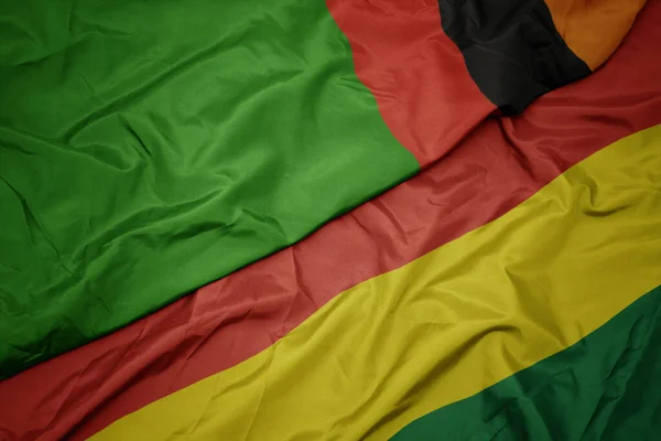 waving colorful flag of bolivia and national flag of zambia. macro
