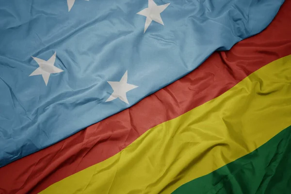 waving colorful flag of bolivia and national flag of Federated States of Micronesia . macro