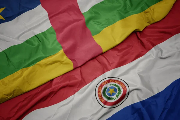 waving colorful flag of paraguay and national flag of central african republic. macro