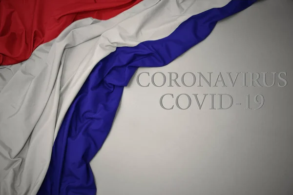 在灰色背景上挥动着色彩艳丽的黑土国旗 文字上写着Coronavirus Covid — 图库照片