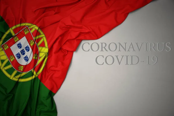 Machając Barwną Flagą Narodową Portugalii Szarym Tle Tekstowym Koronawirusem Covid — Zdjęcie stockowe